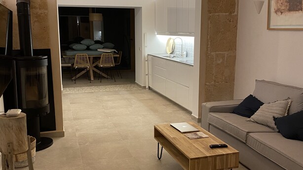 Un interior moderno con un arco de piedra que conduce a un comedor, una mesa de centro de madera y un sofá con cojines.