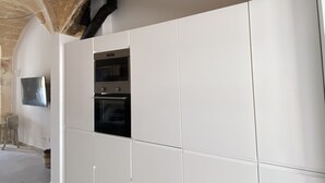 Una cocina moderna con gabinetes blancos, horno integrado y pared de piedra.