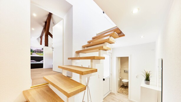 A modern interior with a wooden staircase leading to a second floor.