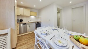 A modern kitchen with white cabinets, stainless steel appliances, and a dining area with a white table set for four.