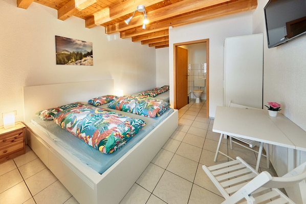 A bedroom with a bed, bedside table, and a desk with a chair.