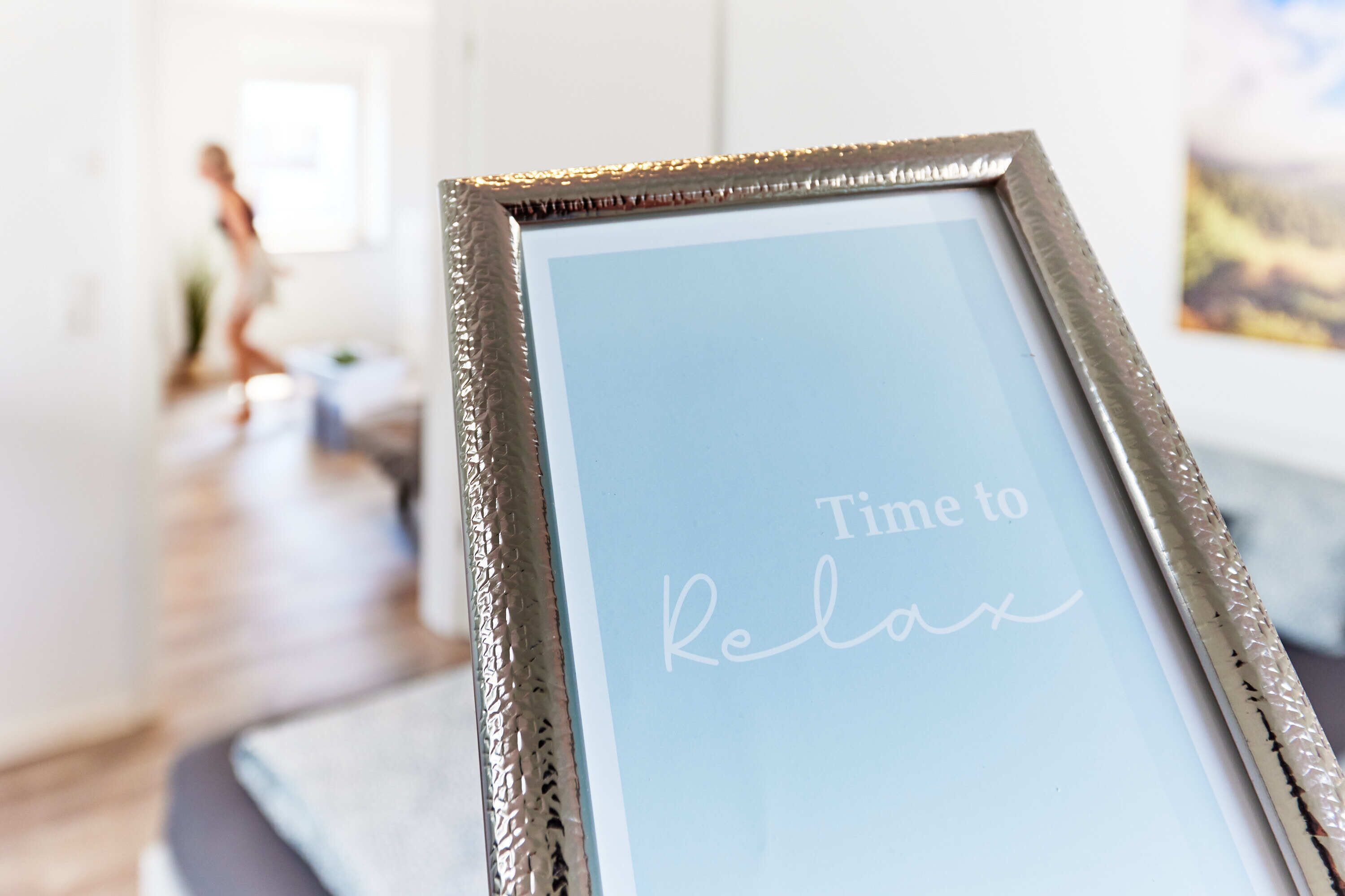 Ein gerahmtes Schild mit dem Aufdruck 'Time to Relax' in einem Raum mit Holzboden und weißen Wänden.