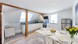 Eine moderne Küche mit weißen Schränken, Holzbalkendecke und einem Essbereich, der für eine Mahlzeit gedeckt ist.