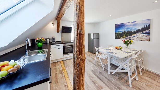 Eine moderne Küche mit Oberlicht, Holzbalken und einem Essbereich mit weißer Möbel.