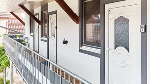 Eine Reihe weißer Türen mit einem Balkongeländer, einem kleinen Blumentopf und einem Schild mit der Nummer 3 an der Wand.