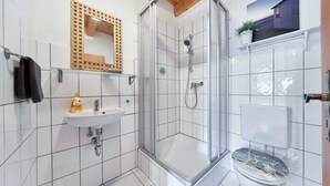 Ein modernes Badezimmer mit Duschkabine aus Glas, Waschbecken und Toilette.