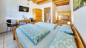 Ein Schlafzimmer mit einem Holzbett, einem Schreibtisch, einem Stuhl und einem an der Wand befestigten Fernseher.