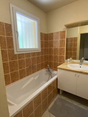 A bathroom with a bathtub, a sink, and a window. - Cozy Apartment with a Mountain View (Briançon)