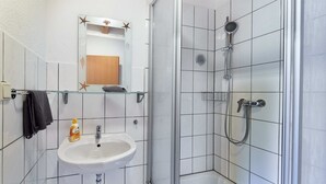 A bathroom with a sink, mirror, and shower. - Beautiful room perfect for families - only 10 minutes walk from Europa-Park (Rust)