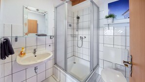 A bathroom with a glass-enclosed shower, a sink with a mirror, and a toilet. - Beautiful room perfect for families - only 10 minutes walk from Europa-Park (Rust)