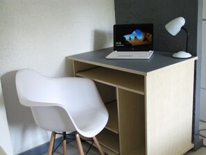 A laptop on a desk with a white chair.