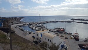 Un puerto deportivo con barcos amarrados, un edificio con puerta azul y una vista despejada del mar.