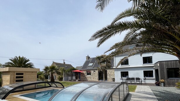 A modern house with a swimming pool, stone walls, and a patio area.