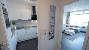 Et moderne køkken med lyse skabe, en marmor bordplade og en indbygget ovn.
