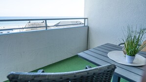 En balkon med havudsigt, et bord med en plante og en fletstol.