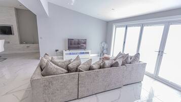En moderne stue med en modulsofa, et fladskærms-tv og et stort vindue.