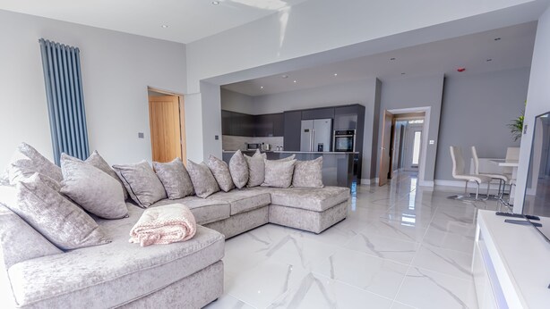 A modern living room with a large sectional sofa, a kitchen in the background, and a dining area. - 4 Bed-sleeps 8- Free Parking-pets-hot Tub (Kelty)
