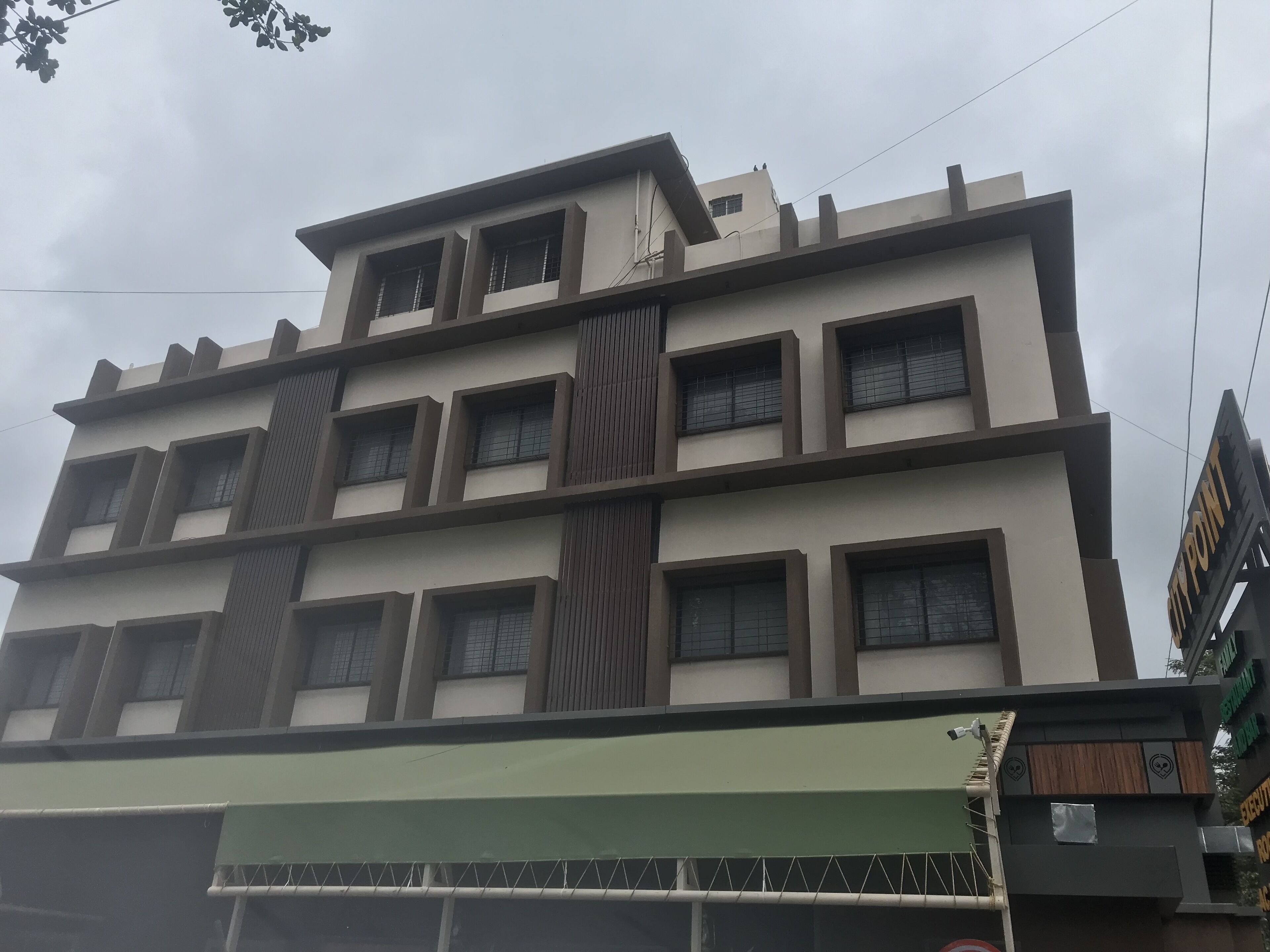 A multi-story building with a modern architectural design, featuring a series of rectangular windows and a green awning at the entrance.