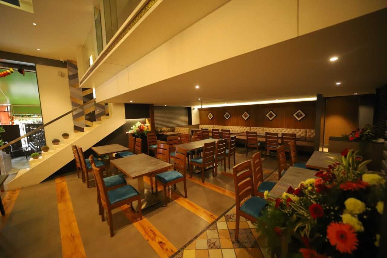 A multi-level restaurant with wooden tables and chairs, a staircase, and a buffet area.