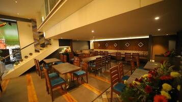 A multi-level restaurant with wooden tables and chairs, a staircase, and a buffet area.
