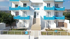 A modern two-story building with balconies, a staircase leading to the entrance, and a sign indicating it is a studio/apartment complex. - Pittas Studios Kardamena 300 Meters From the Beach (Kos)
