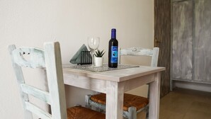 A dining table with a bottle of wine, a glass, and a small potted plant. - Pittas Studios Kardamena 300 Meters From the Beach (Kos)