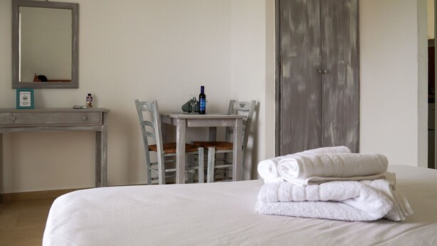 A hotel room with a bed, a desk, a chair, and a mirror. - Pittas Studios Kardamena 300 Meters From the Beach (Kos)