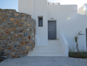 A modern building with a stone wall and a grey door.