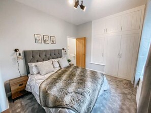 A bedroom with a large bed, a wardrobe, and a nightstand.