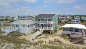 A beachfront property with multiple houses, some elevated on stilts, and a sandy beach area.