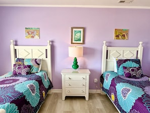 Une chambre avec deux lits, une table de chevet avec une lampe et des œuvres d’art murales.