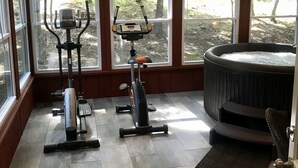 Ein Heimfitnessraum mit Trainingsgeräten, einem Deckenventilator und einer Whirlwanne.