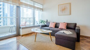 A modern living room with a grey sofa, a round coffee table, and a large window with blinds.