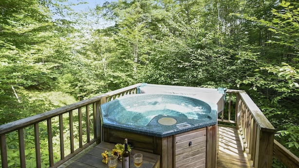 Un bain à remous sur une terrasse en bois, entouré d’une végétation luxuriante.