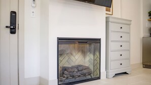 A modern living room with a fireplace, a flat-screen TV mounted above it, and a white dresser with drawers. - Casa Valerio Unit 6C (Santa Barbara)