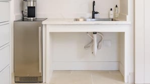 A modern kitchen with a built-in air conditioner, a sink, a coffee machine, and a small shelf with glassware. - Casa Valerio Unit 6C (Santa Barbara)