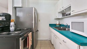 A compact kitchen with a stove, refrigerator, microwave, and a sink. - The Funky Cactus House - Team Joseph Ellen (Jacksonville)