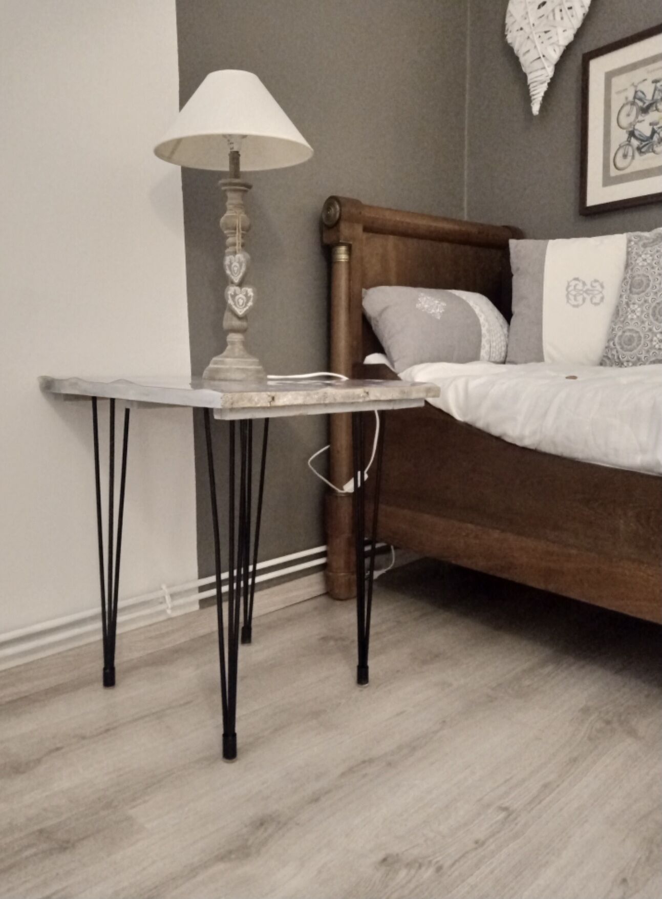 A bedroom with a wooden bed, a bedside table with a lamp, and a wall-mounted decorative item.