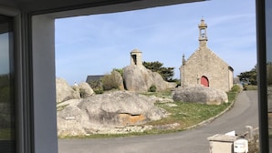 Eine steinerne Kirche mit einem Glockenturm, großen Felsen und einer roten Tür.