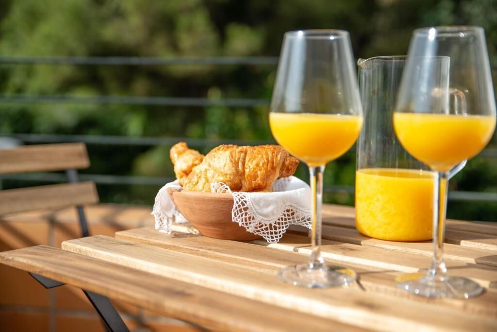 A wooden table with a bowl of croissants and two glasses of orange juice.