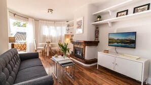 Ein Wohnzimmer mit Sofa, Kamin, Fernseher und Essbereich.