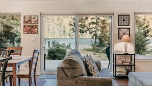 A living room with a sofa, a dining table with chairs, and a view of a forest through large sliding glass doors. - 47MF - WiFi - Fireplace - Sleeps 6 3 Bedroom Home by RedAwning (Maple Falls)