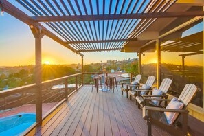 Een houten terras met een pergola, buitenmeubels en een zwembad.