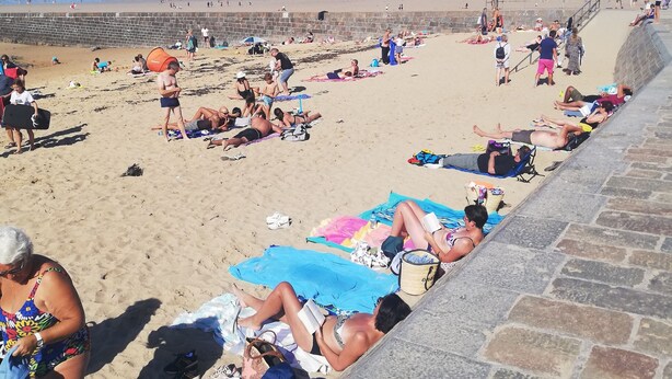 Une scène de plage où l’on voit des gens bronzer et se détendre sur le sable.