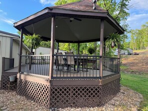 Eine überdachte Terrasse im Freien mit Geländer, Sitzgelegenheiten und einer Pergola.
