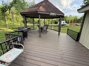 Eine überdachte Terrasse mit Pavillon, Grill und Gartenmöbeln.