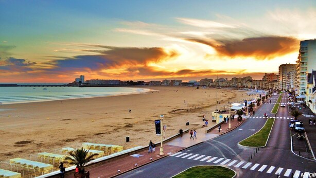 A beachside promenade with a wide road, pedestrian paths, and buildings in the background. - Lovely mobile home in a 4-star residential estate in Les Sables D'Olonne (Les Sables-d'Olonne)