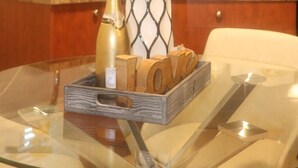 A kitchen with wooden cabinets, a glass table with a vase of flowers, and a bottle. - Burnaby Cozy suite Near Skytrain (Burnaby)