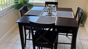 Een eetruimte met een tafel voor vier personen, omringd door stoelen, met uitzicht op groen buiten.