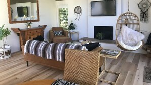 A living room with a sofa, armchair, hanging chair, and a fireplace. - Casa del Sol - Peaceful home away from home. (Santa Barbara)